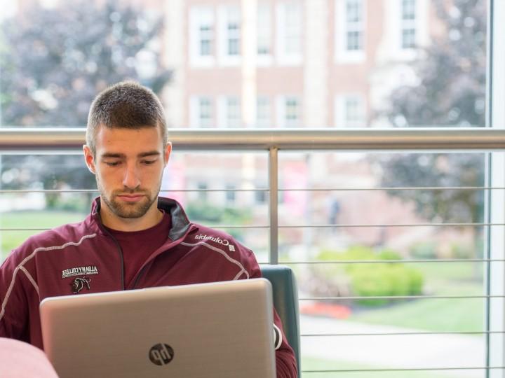 A student sitting with laptop at ACPHS lounge