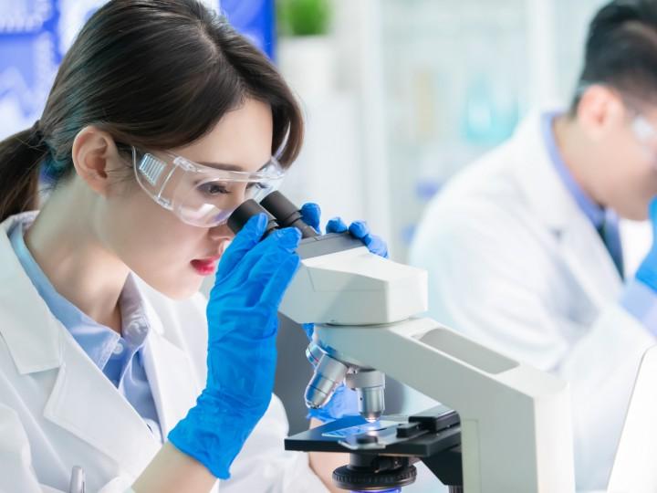 A woman looks into microscope